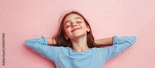 Happy young girl in a blue and white striped shirt, lying on her back with her arms behind her head and smiling.