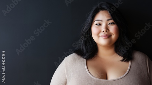 Portrait of a smiling Asian woman with dark hair against a black background.