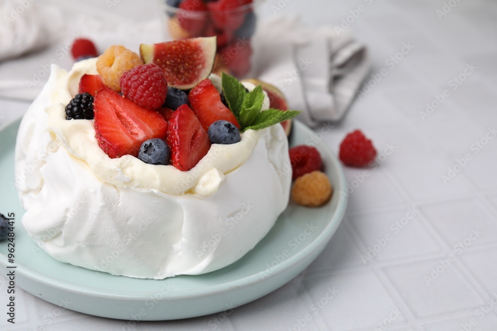 Pavlova cake (meringue dessert) with whipped cream, fresh berries, mint and fig on white tiled table, closeup Pavlova cake (meringue dessert) with whipped cream, fresh berries, mint and fig on white tiled table, closeup