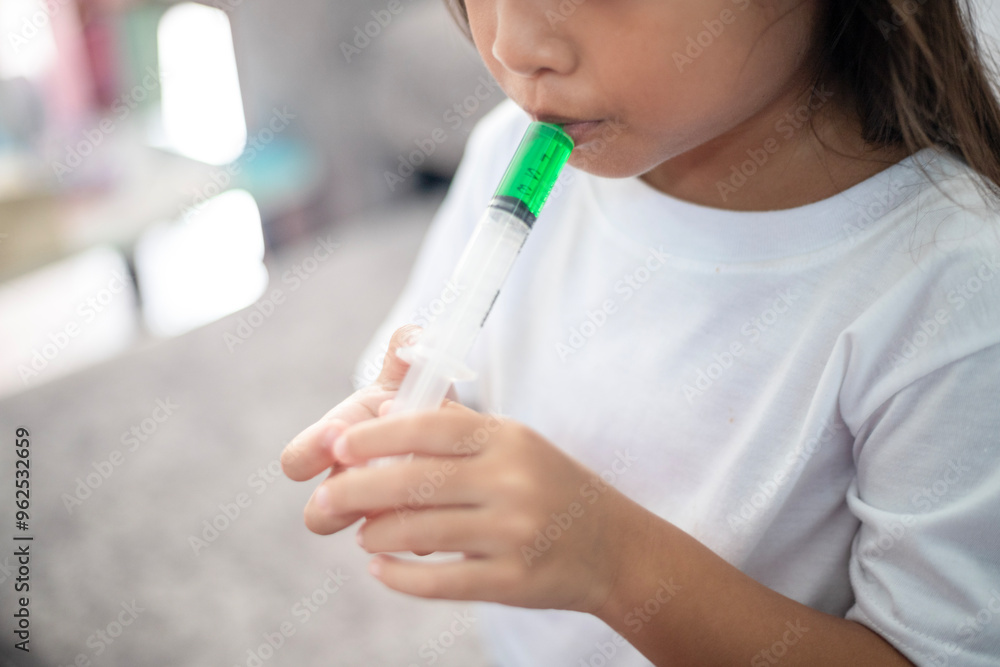 Naklejka premium A young girl is sitting on the floor with a syringe in her mouth.
