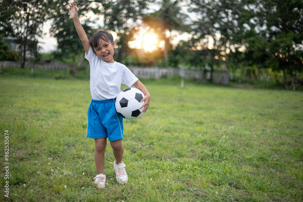 A young girl is holding a soccer ball in a park. She is smiling and she is enjoying herself A young girl is holding a soccer ball in a park. She is smiling and she is enjoying herself
