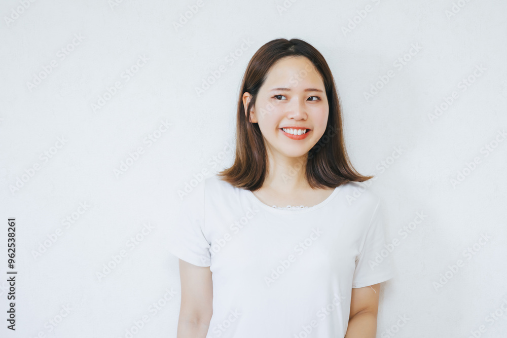 白い壁の前で笑顔でいる女性
A woman smiling in front of a white wall 白い壁の前で笑顔でいる女性
A woman smiling in front of a white wall
