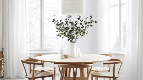 White dining room with a round table, wooden chairs, and a statement pendant light hanging overhead.