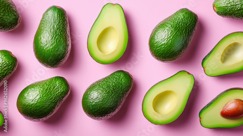 Fresh avocados, halved and whole, arranged on a vibrant pink background, showcasing their green outer skin and creamy interior.