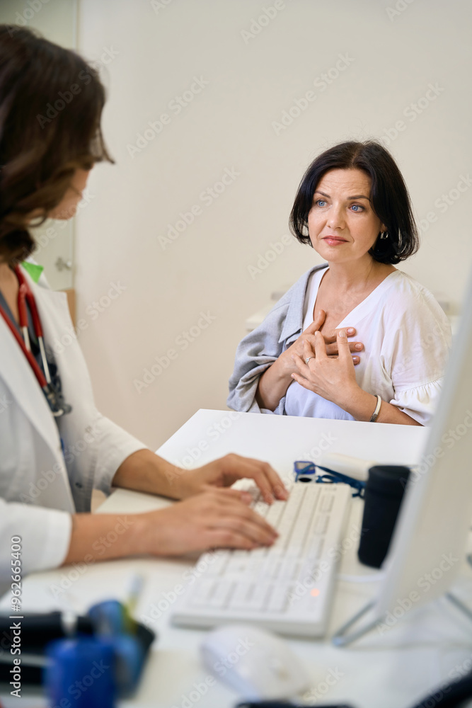 Middle-aged patient complains to the doctor about chest pain Middle-aged patient complains to the doctor about chest pain