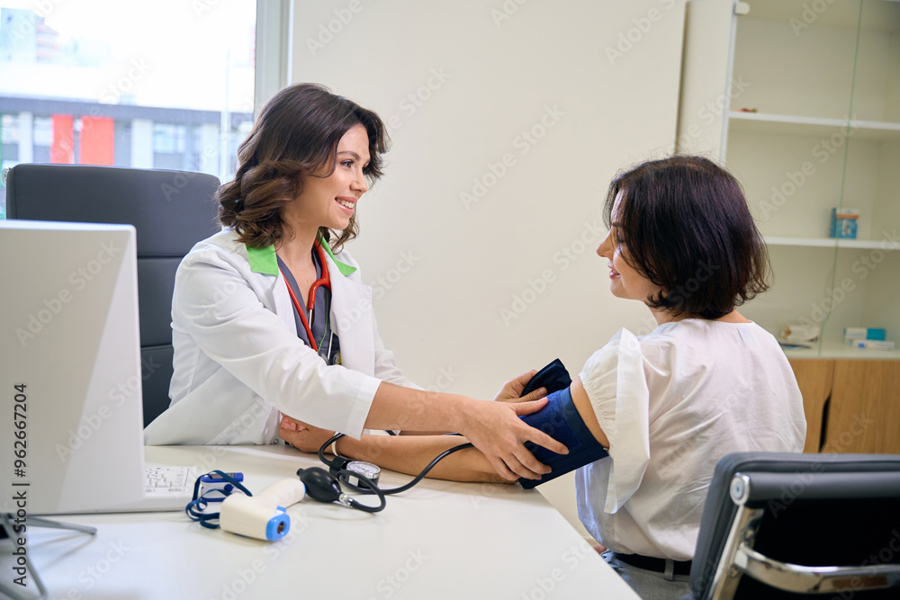 Young doctor measures a patients blood pressure at clinic appointment Young doctor measures a patients blood pressure at clinic appointment