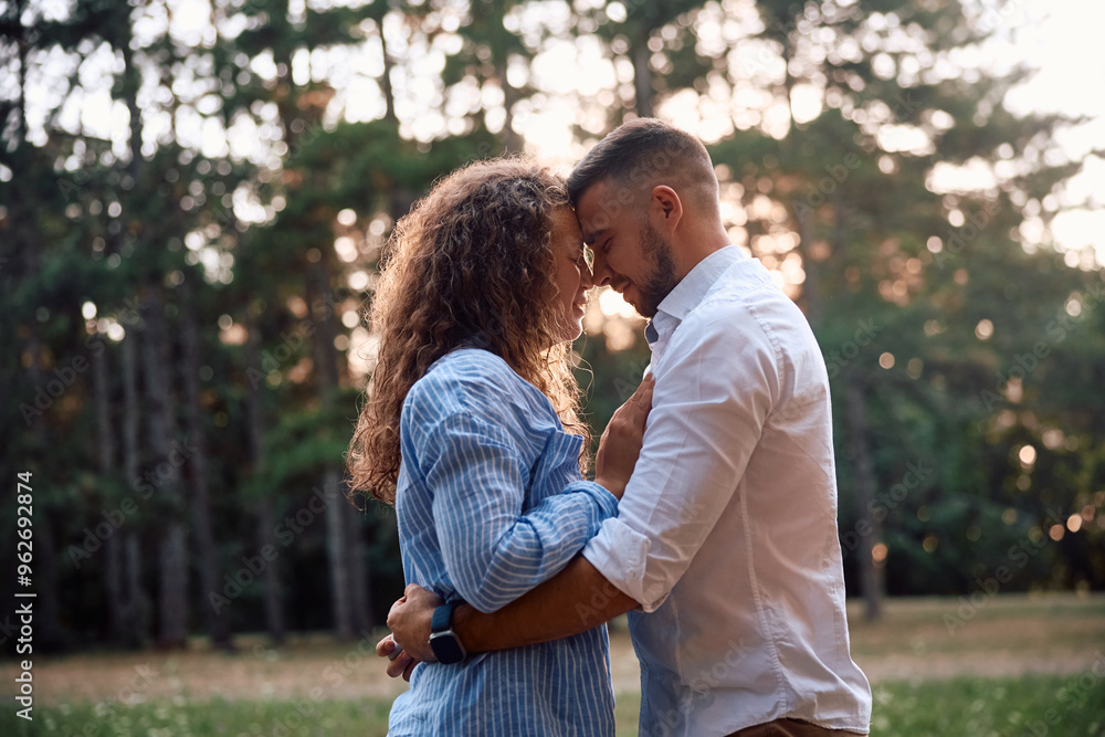 Young loving couple standing face to face in nature at sunset.