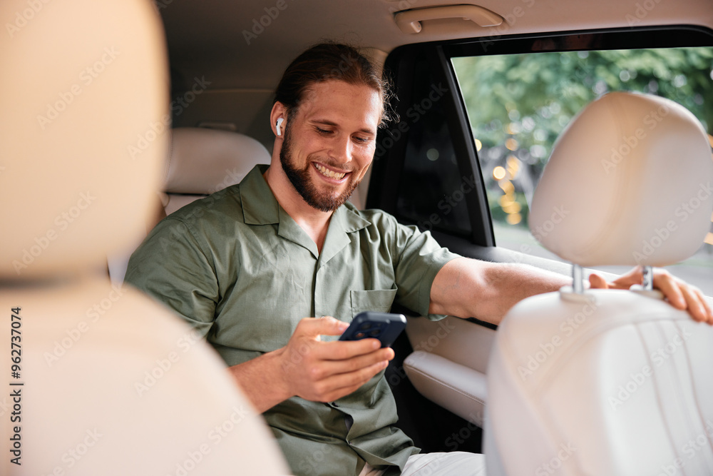 Smiling man using smartphone with wireless earbuds in a car interior Smiling man using smartphone with wireless earbuds in a car interior