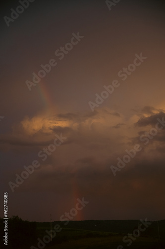 Rainbow going through storm clouds on dramatic evening