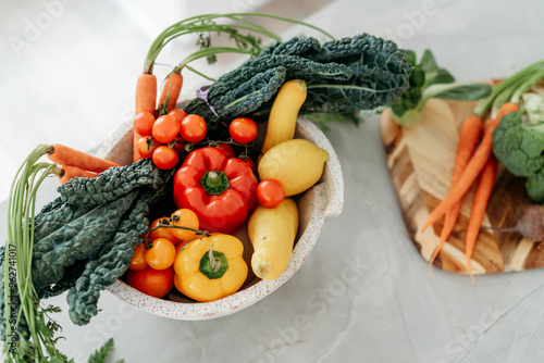 Stone bowl of bright vegetables on marble countertop photo