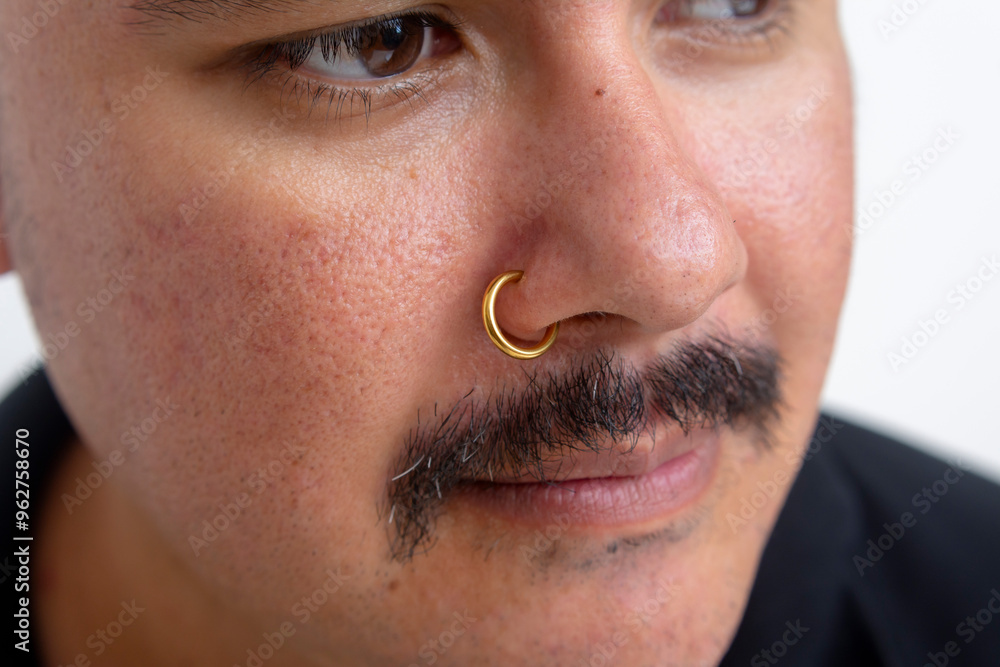 Close up of a gold Clip-on Hoop nose ring attached on a man's nose. Slide spring style fake piercing.