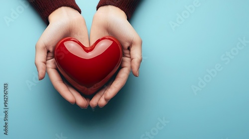 A pair of hands gently holding a red heart, symbolizing love, care, and compassion on a soothing blue background.