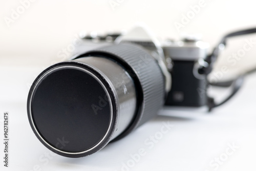 A legacy macro lens attached to a vintage SLR photography camera, isolated in white.