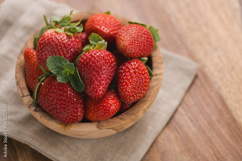 Ripe strawberries in wooden bowl on wood background with copy space Ripe strawberries in wooden bowl on wood background with copy space