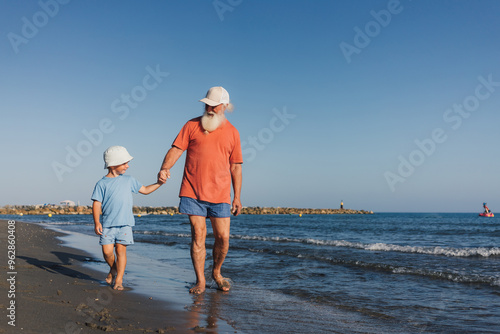 Grandfather and Child Enjoying a Stroll on the Beach photo