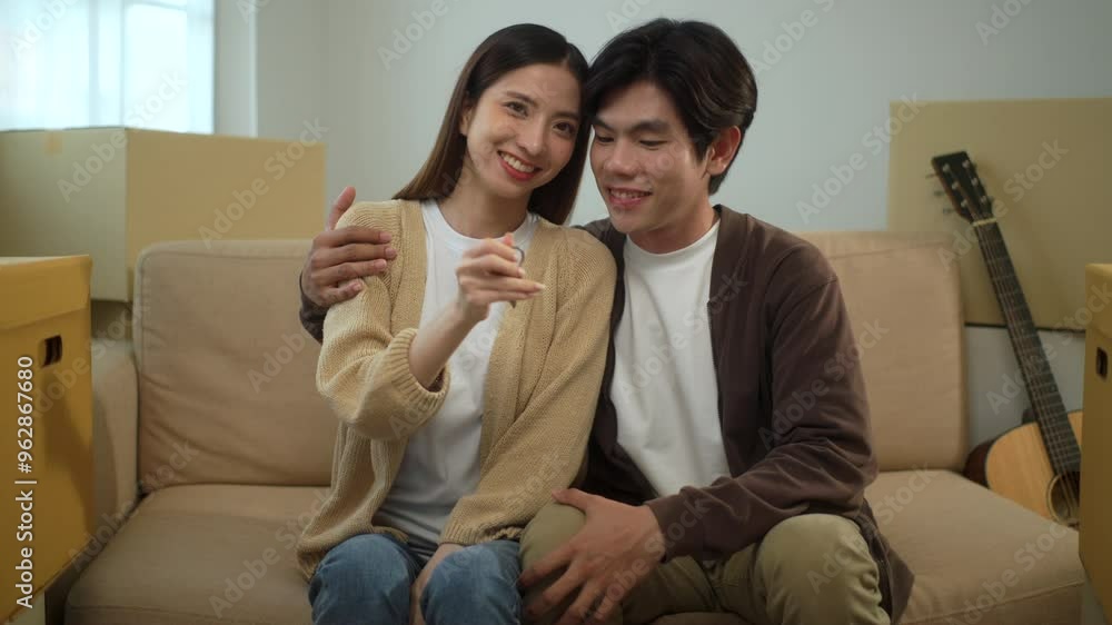 Young cheerful couple smiling to each other and looking at camera while girlfriend holding house key after moving to new house with pile of cardboard boxes, relocating real estate apartment concept.
Young cheerful couple smiling to each other and looking at camera while girlfriend holding house key after moving to new house with pile of cardboard boxes, relocating real estate apartment concept.