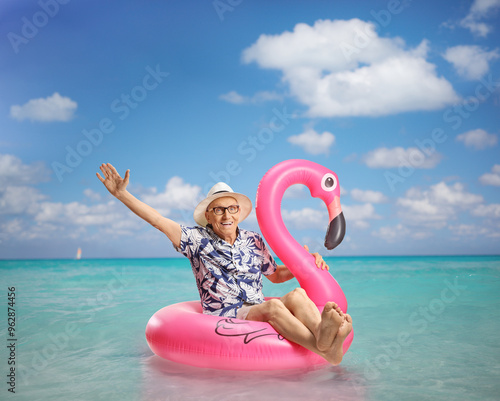 Elderly man sitting on a big inflatable flamingo rubber ring