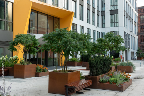 Large flowerbeds with lush greenery in urban environment among office buildings. Landscaping, beautiful flowerbeds in urban environment. High quality photo