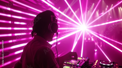 A DJ wearing headphones performs at a nightclub, surrounded by vibrant pink lighting and laser beams. The energetic atmosphere and dynamic visuals create a captivating nightlife experience.