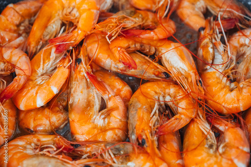 A close-up view of the undivided shrimp fried in oil in a frying pan. photo