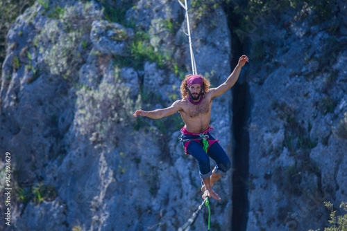 A tightrope walker walks along a cable stretched over a canyon.