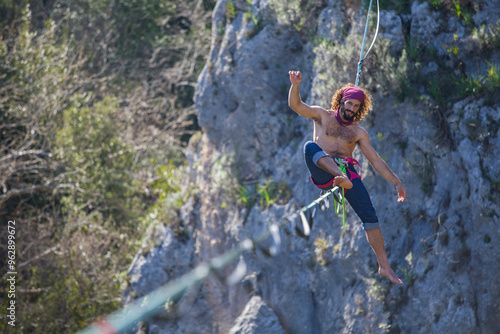 A tightrope walker walks along a cable stretched over a canyon.