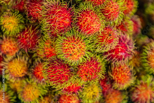 view of a bunch of red, yellow and green rambutan fruits with the spiky skin. photo