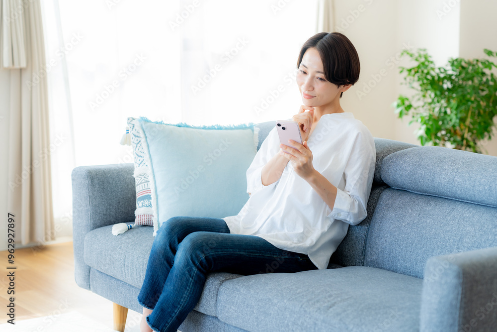部屋でスマホを操作するミドル女性 部屋でスマホを操作するミドル女性