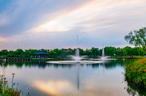 Buyeo-gun, Chungcheongnam-do, South Korea - July 10, 2020: Long exposure and sunset view of lily flowers with fountain and a pavilion at Gungnamji Pond photo