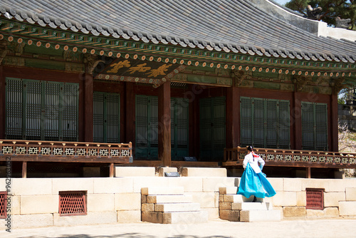 Changgyeonggung Palace, Jongro-Ku, Seoul, South Korea - March 30, 2021: Young Korean female with blue Hanbok(Korean traditional clothes) is on stairs of Yanghwadang Hall photo