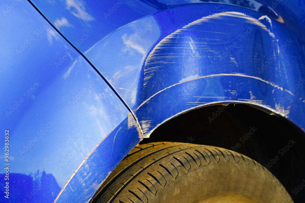 Closeup of damaged car front fender, deep dent and scratched arch, impact of collision and the need for vehicle body repair..