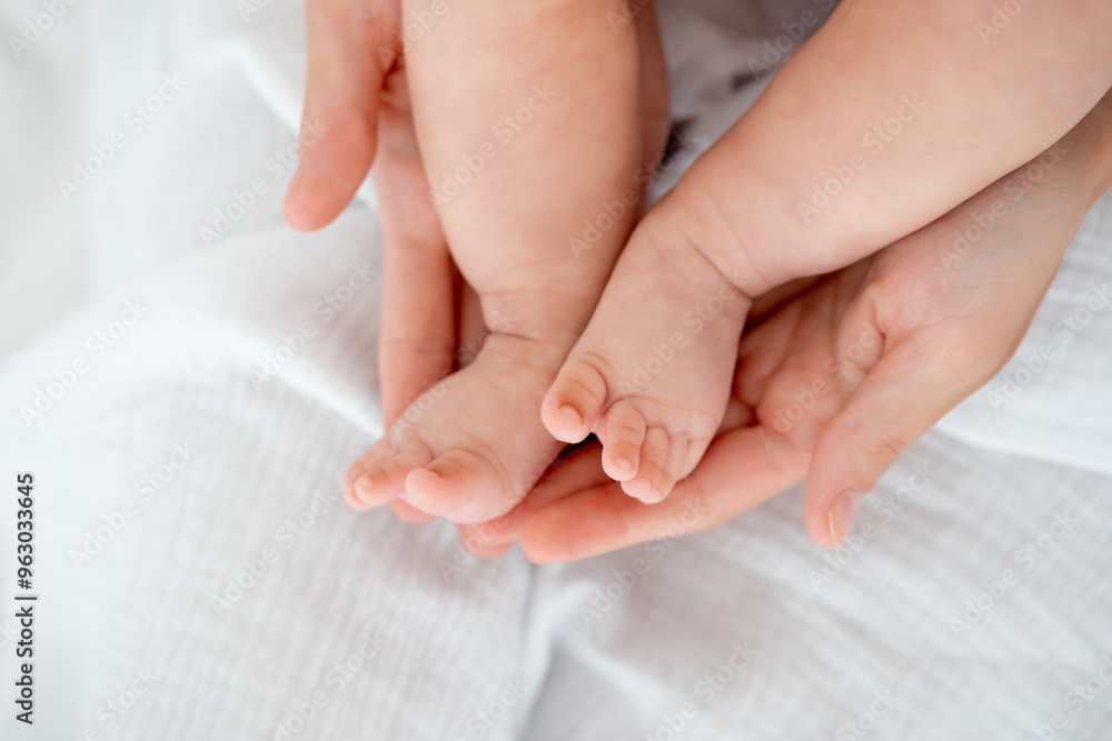mom's hands hold the legs of a newborn baby, legs in focus, pink baby heels mom's hands hold the legs of a newborn baby, legs in focus, pink baby heels