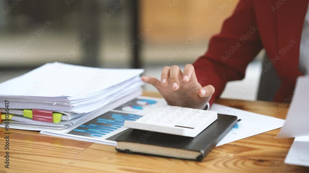 Businesswoman Calculating Figures: A close-up shot of a businesswoman's hand using a calculator, surrounded by a pile of documents and financial reports, emphasizing the detail-oriented and analytical Businesswoman Calculating Figures: A close-up shot of a businesswoman's hand using a calculator, surrounded by a pile of documents and financial reports, emphasizing the detail-oriented and analytical