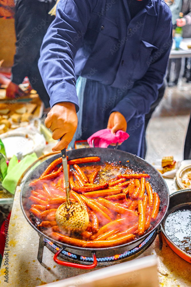 Obraz premium A Basque farmer (Baserritarra) roasting Txistorra (fresh chorizo) to prepare Talos, a traditional street food served during the Day of Saint Thomas.