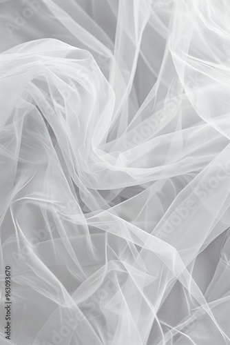 Close-up view of white fabric with subtle sheen, soft and delicate texture. Fabric folded in half revealing intricate pattern of small lines and curves on gray background.