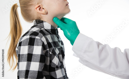 The hand of a pediatrician doctor probes the sore throat of a seven-year-old girl who has a sore throat. Inflammation of the lymph nodes, bacterial and viral infection. Copy space for text photo