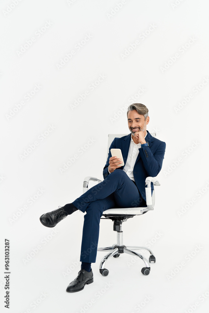 Happy middle aged business man using phone sitting in office chair isolated on white background. Happy mature businessman in his 40s with smartphone in hands looking at cellphone, full body photo. Happy middle aged business man using phone sitting in office chair isolated on white background. Happy mature businessman in his 40s with smartphone in hands looking at cellphone, full body photo.