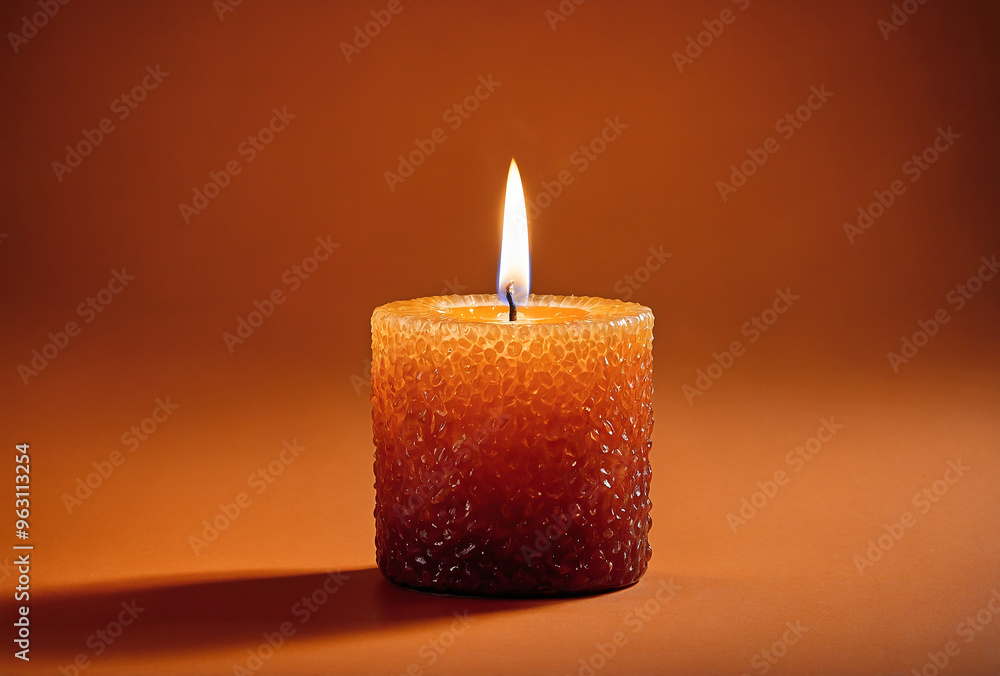 Single glowing candle burning with a flickering flame on an orange background Single glowing candle burning with a flickering flame on an orange background