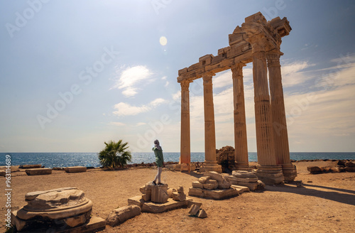 Obraz na płótnie A woman in burka posing against breathtaking view of the Temple of Apollo ruins in Side, Turkey, with the Mediterranean Sea in the background. w salonie