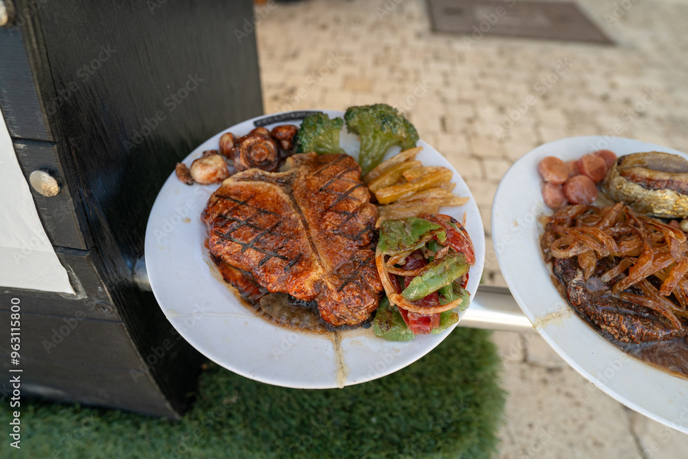 A realistic fake food display outside a restaurant featuring steak, sides and veggies, designed to attract customers with its detailed presentation. Marketing tool