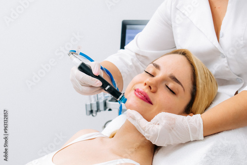 Relaxing beauty treatment in a modern cosmetic clinic. Woman enjoying a hydrolifting procedure, achieving radiant and youthful skin. Perfect for showcasing advanced skincare solutions.