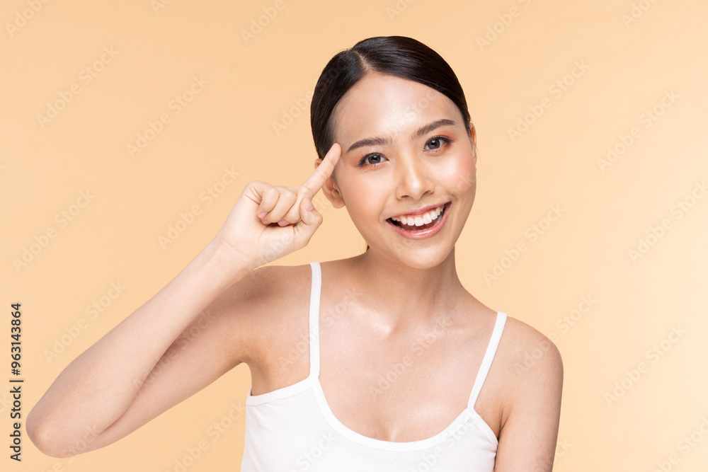 Cheerful woman pointing to her temple, showcasing positivity and creativity against a light background. Cheerful woman pointing to her temple, showcasing positivity and creativity against a light background.