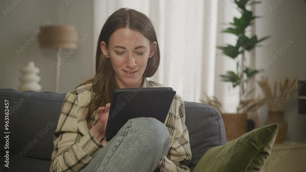 Women Scrolling Tablet While Sitting on Couch Women Scrolling Tablet While Sitting on Couch