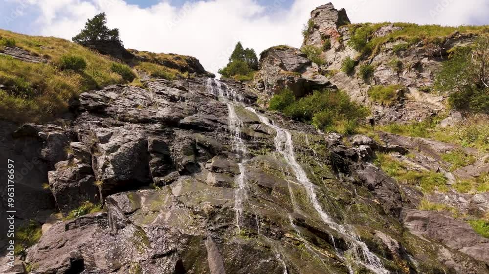 Top cinematic aerial view to the small Capra Waterfall, Transfagaras, Romania. Romanian wild nature and landscape from above. Close up video. Top cinematic aerial view to the small Capra Waterfall, Transfagaras, Romania. Romanian wild nature and landscape from above. Close up video.