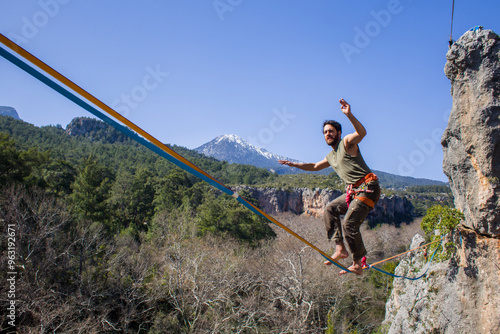 A tightrope walker walks along a cable stretched over a canyon.