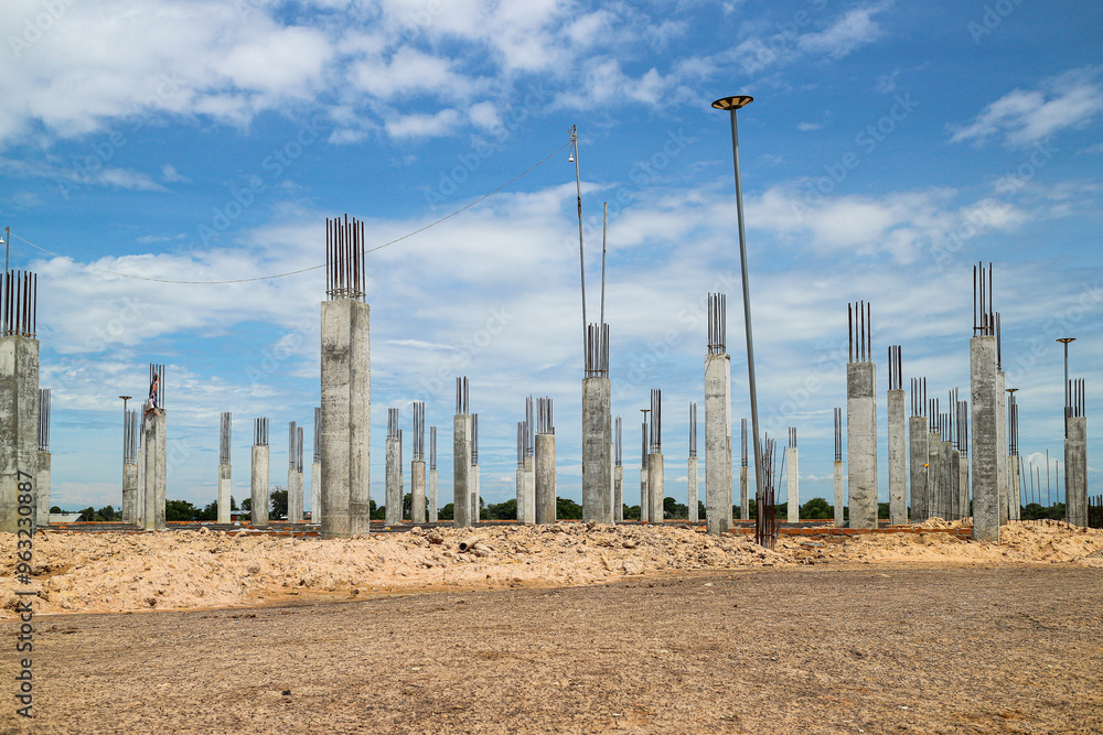 Wide angle view of Concrete pillars rise against a blue sky marking the foundation of a future structure. Construction Site with Concrete Pillars Background. Wide angle view of Concrete pillars rise against a blue sky marking the foundation of a future structure. Construction Site with Concrete Pillars Background.