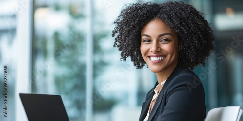 Smiling businesswoman using a laptop during a meeting in a high-rise office.