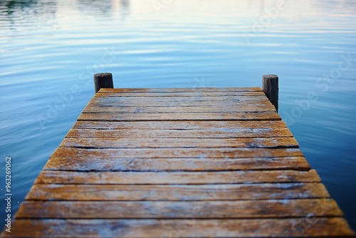 A weathered wooden pier stretches into clear, calm blue water, creating a serene and peaceful atmosphere.
