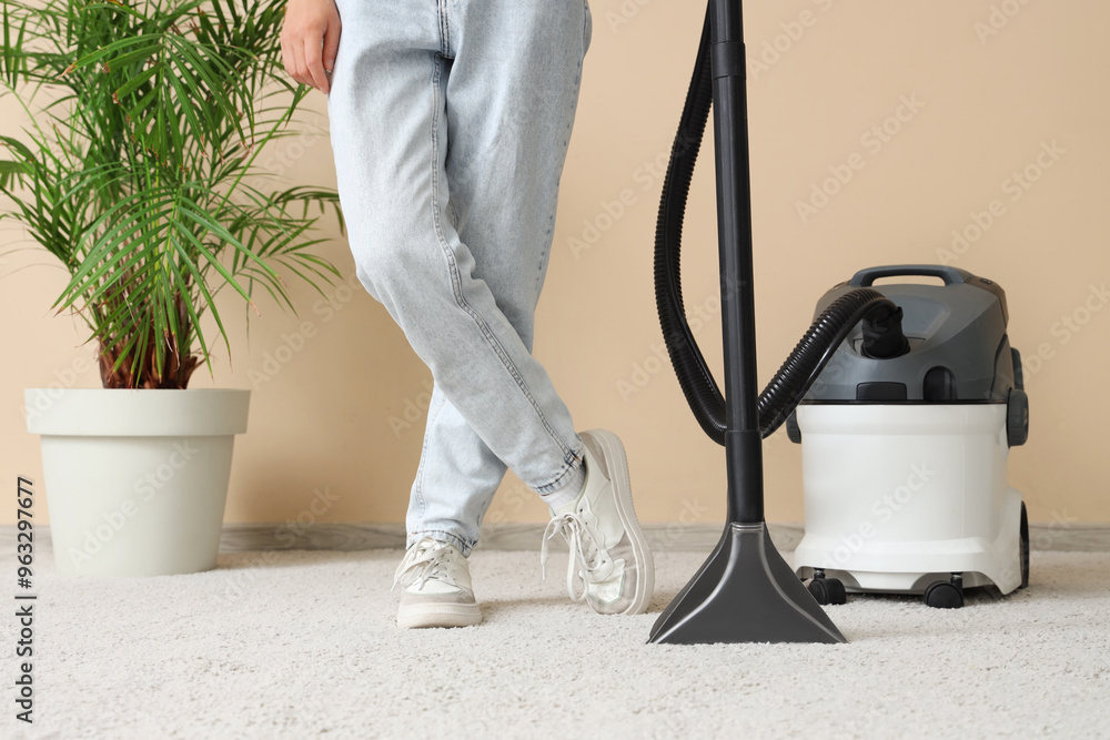 Fototapeta premium Woman cleaning carpet with vacuum cleaner at home