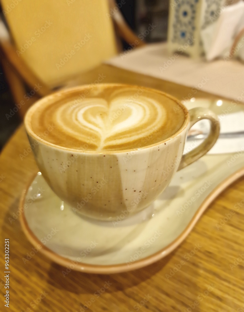 Cup of cappuccino coffee with a heart-shaped pattern. Composition in beige and brown tones.